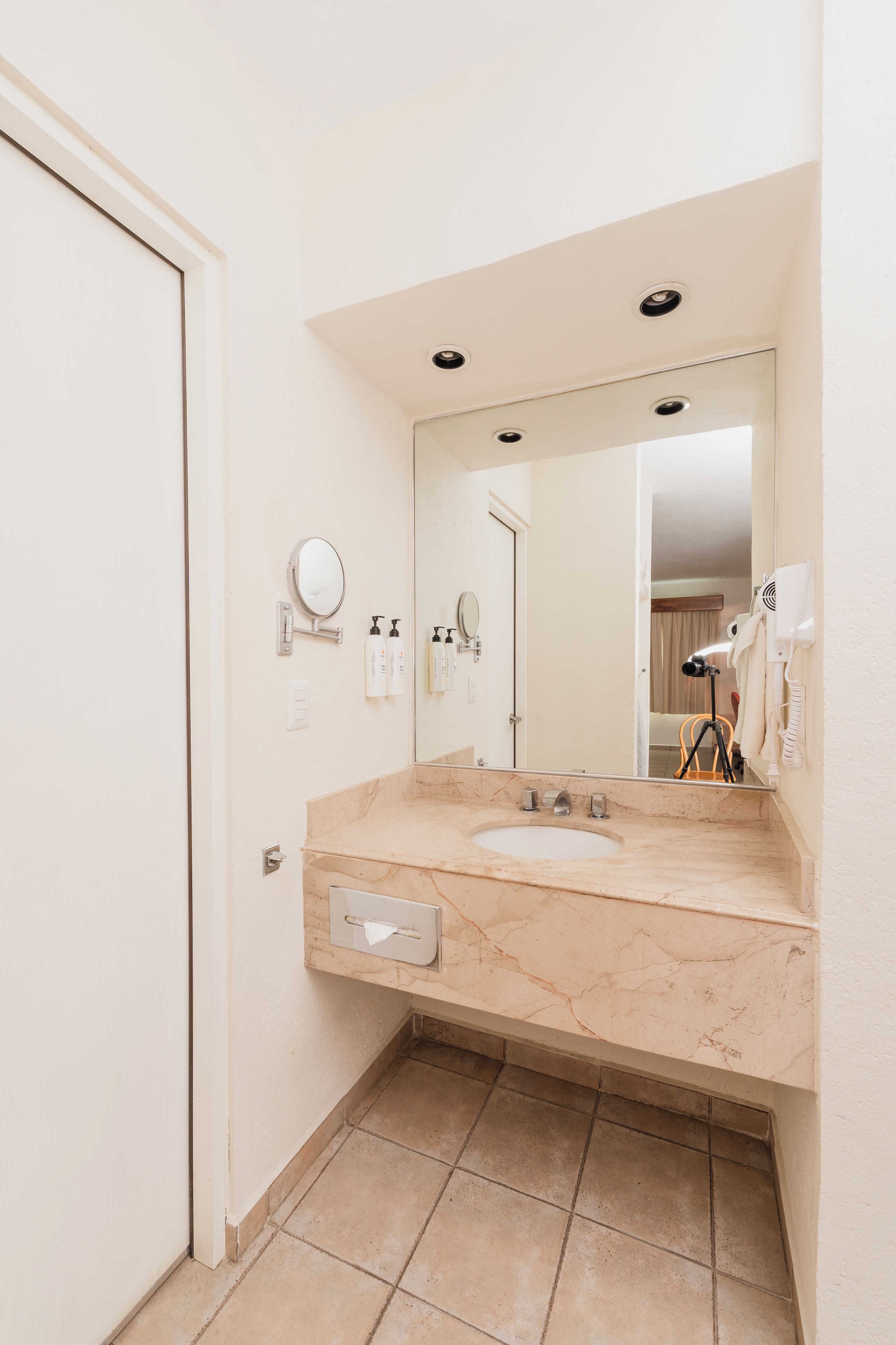 A bathroom with a marble sink, a mirror, a towel rack, and a hairdryer.