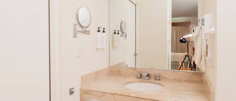 Une salle de bain avec un lavabo en marbre, un miroir, un porte-serviettes et un sèche-cheveux.
