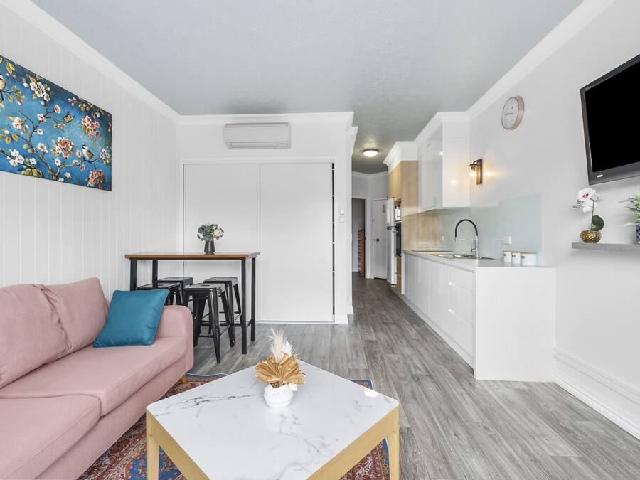 Una sala de estar moderna con un sofá rosa, una mesa de centro y un cuadro en la pared.