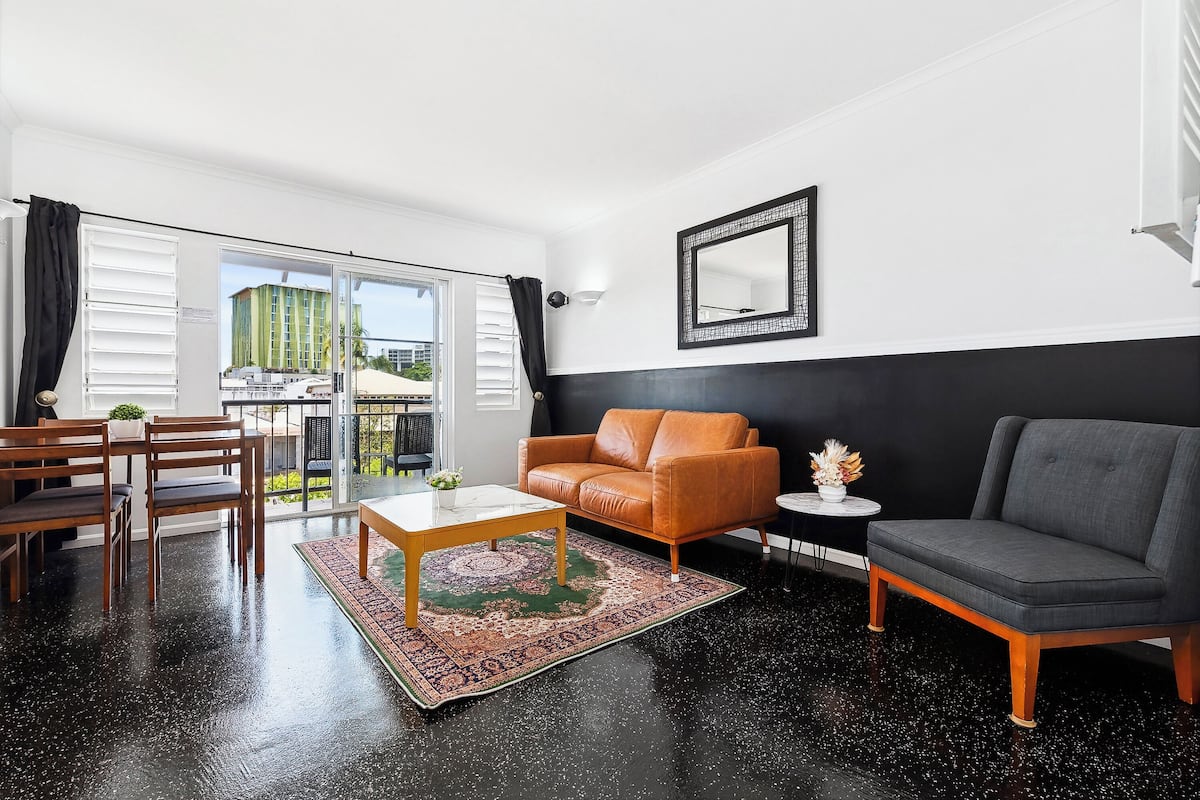 Un salon moderne aux couleurs contrastées, en noir et blanc, comprenant un canapé, un fauteuil, une table basse et une petite table d’appoint.