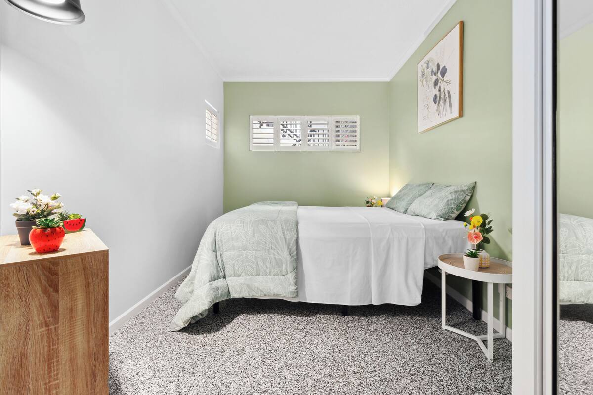 Une chambre à coucher avec un lit, une petite table et une table de chevet en bois.