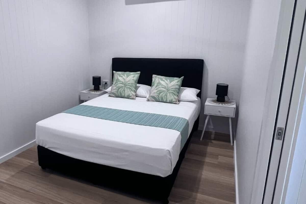 Une chambre à coucher bien rangée, avec un lit, deux tables de chevet et une petite table d’appoint.