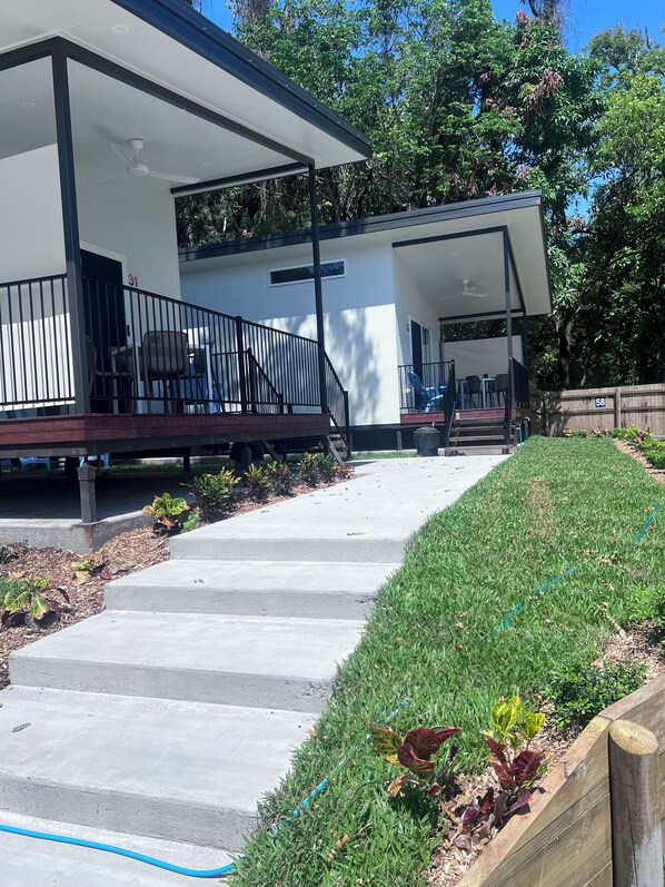 A modern building with a covered outdoor seating area and a staircase leading to a second level. - Ellis Beach Oceanfront Bungalows (Ellis Beach)