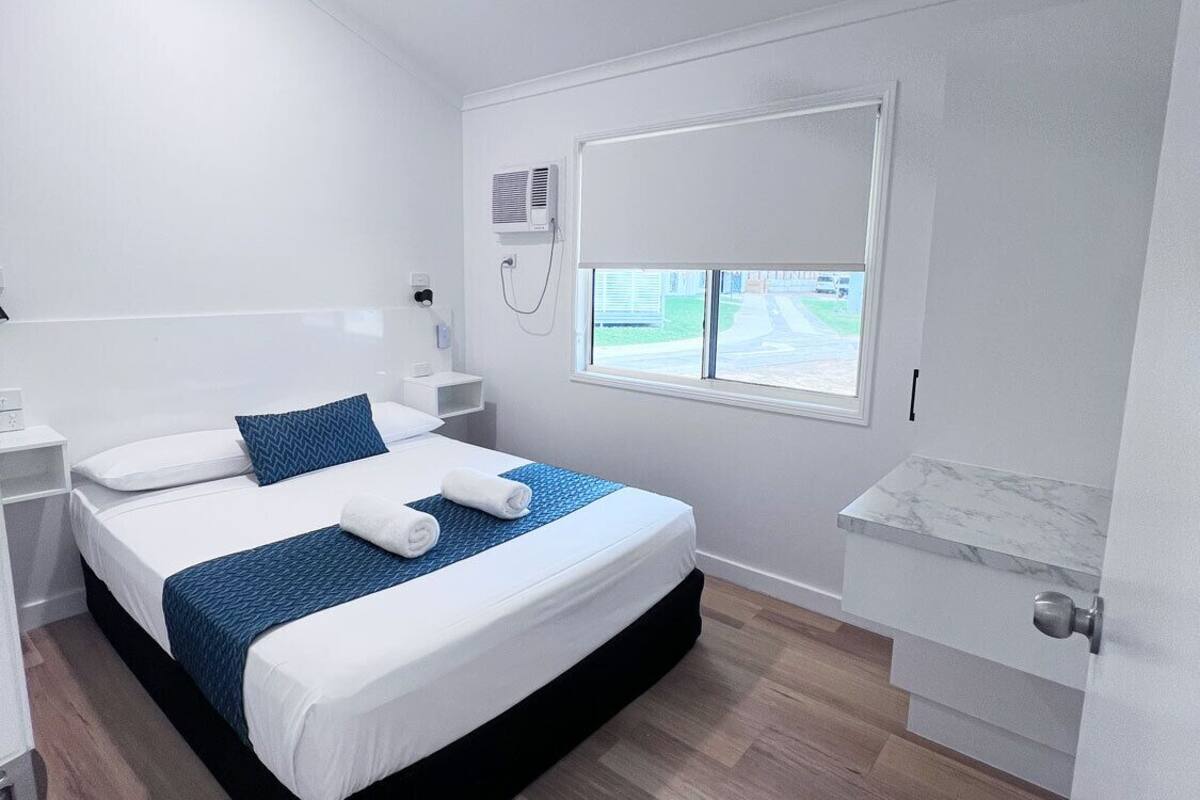Une chambre d’hôtel moderne dotée d’un grand lit, d’un ventilateur de plafond, d’un appareil de climatisation, d’une fenêtre avec vue et d’un comptoir en marbre.