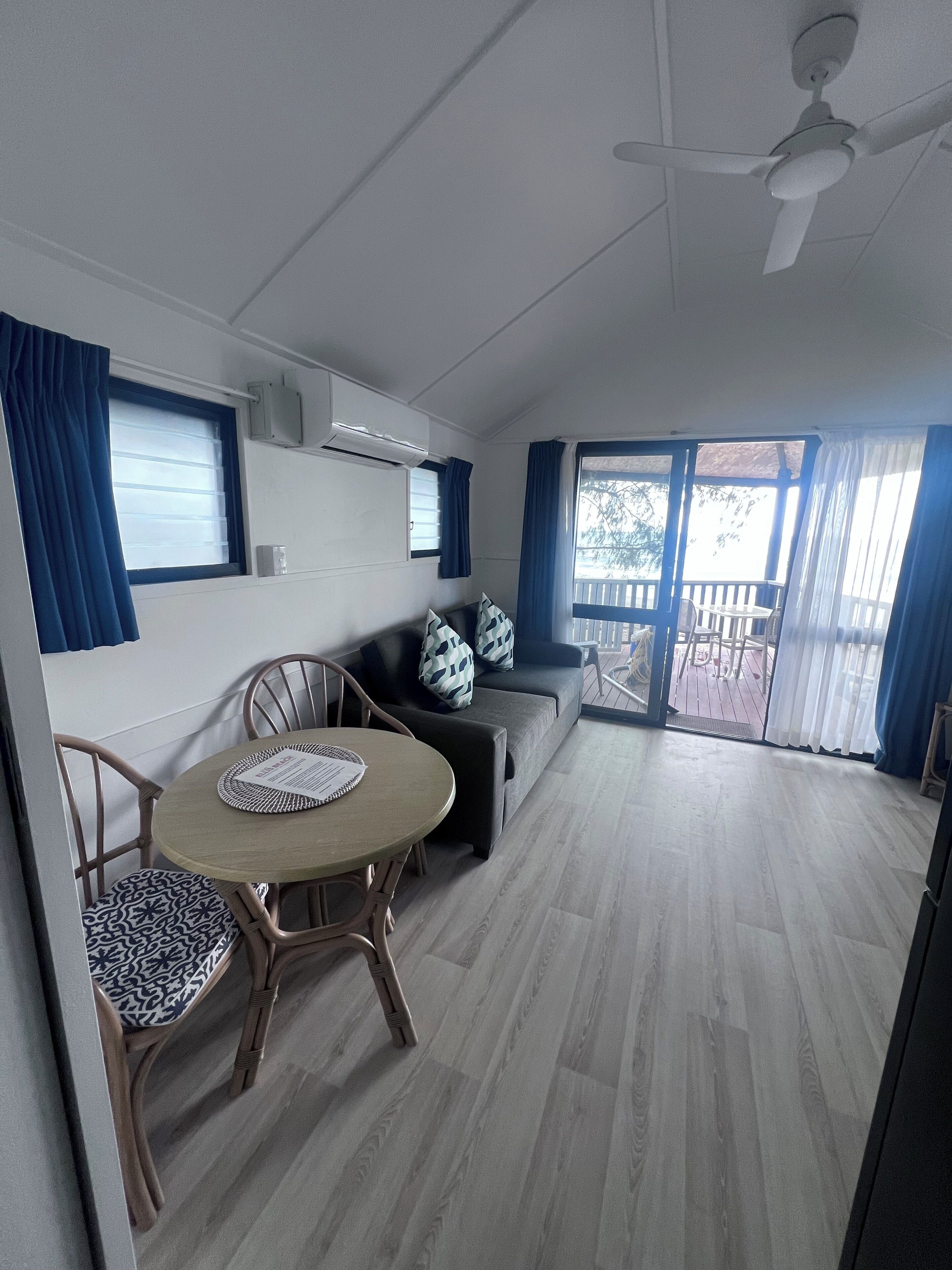 Un espace de vie compact comprenant une table à manger, des chaises, un canapé et un ventilateur de plafond.