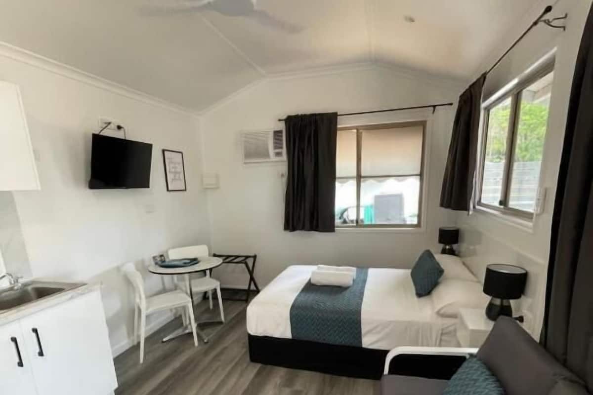 Une pièce moderne et bien éclairée, comprenant un lit, un canapé, un bureau et un téléviseur.