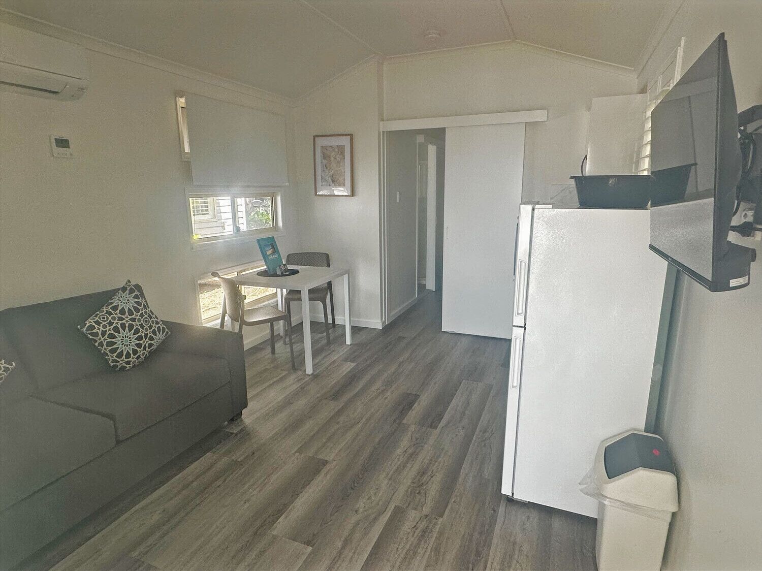 A compact living space with a sofa, a dining table, and a refrigerator.