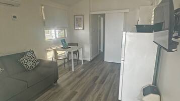 A compact living space with a sofa, a dining table, and a refrigerator.