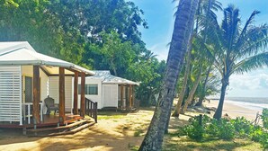 Une propriété située en bord de mer, comprenant deux chalets, chacun doté d’une véranda et offrant une vue sur l’océan.