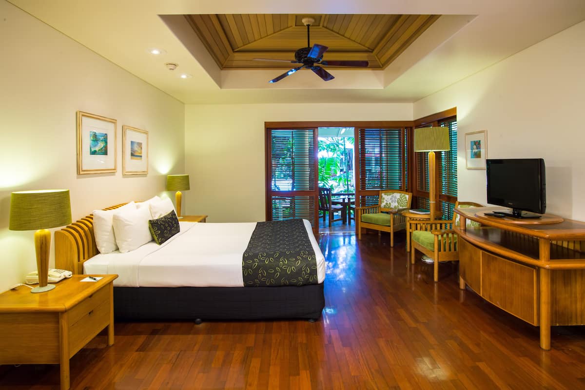 Habitación de hotel con cama, escritorio, televisión y vistas al exterior.