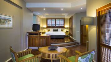 A hotel room with a bed, a desk with a computer, a chair, a table, and a window with blinds.