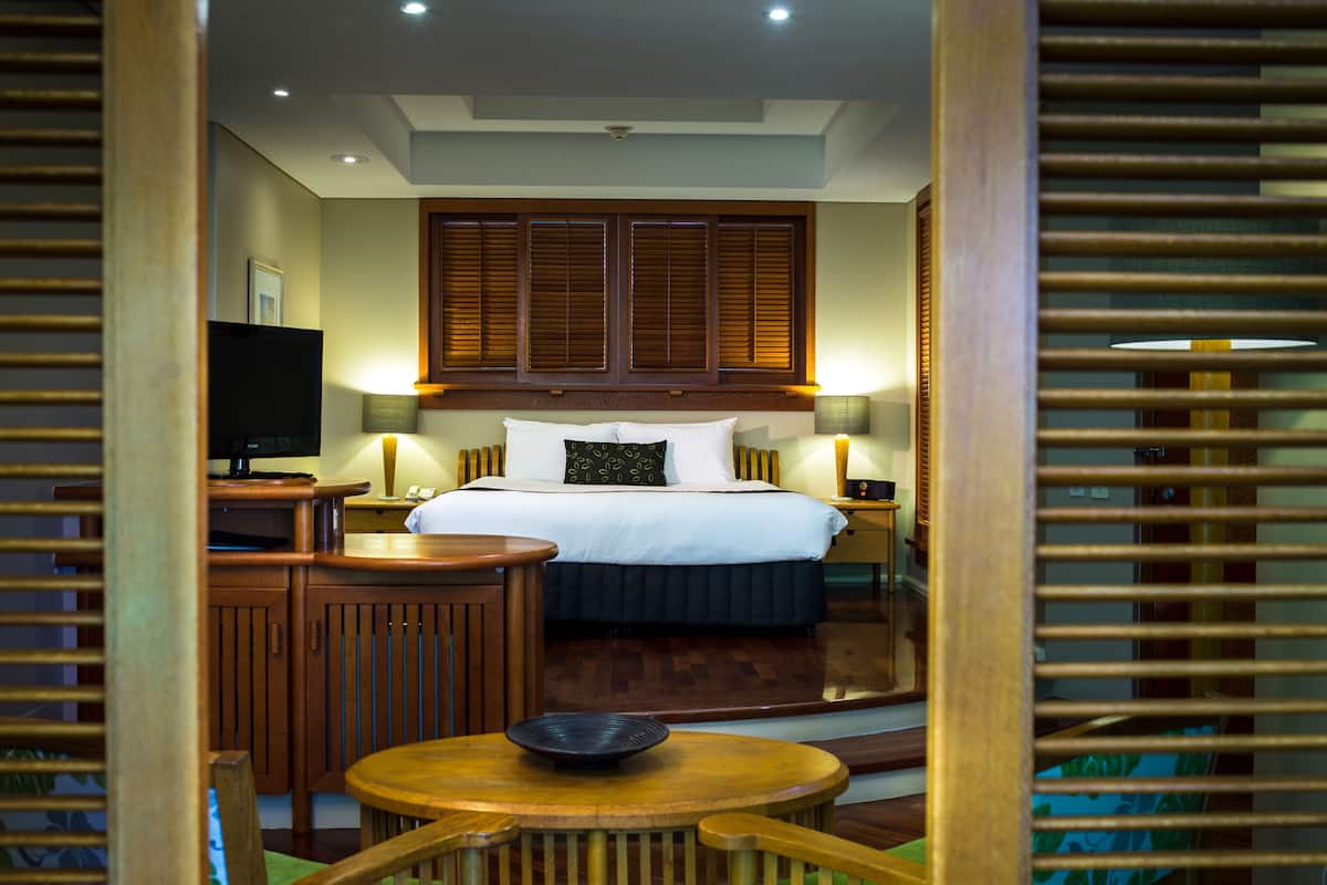 Una habitación de hotel con una cama, lámparas de noche, un televisor, un escritorio y una silla.