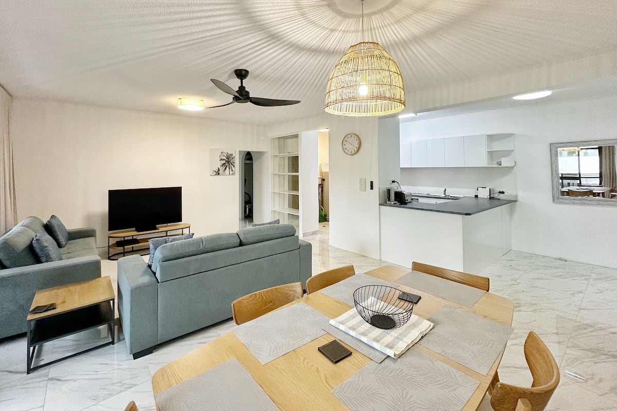 A modern living room with a sofa, TV, and dining area with a table and chairs.