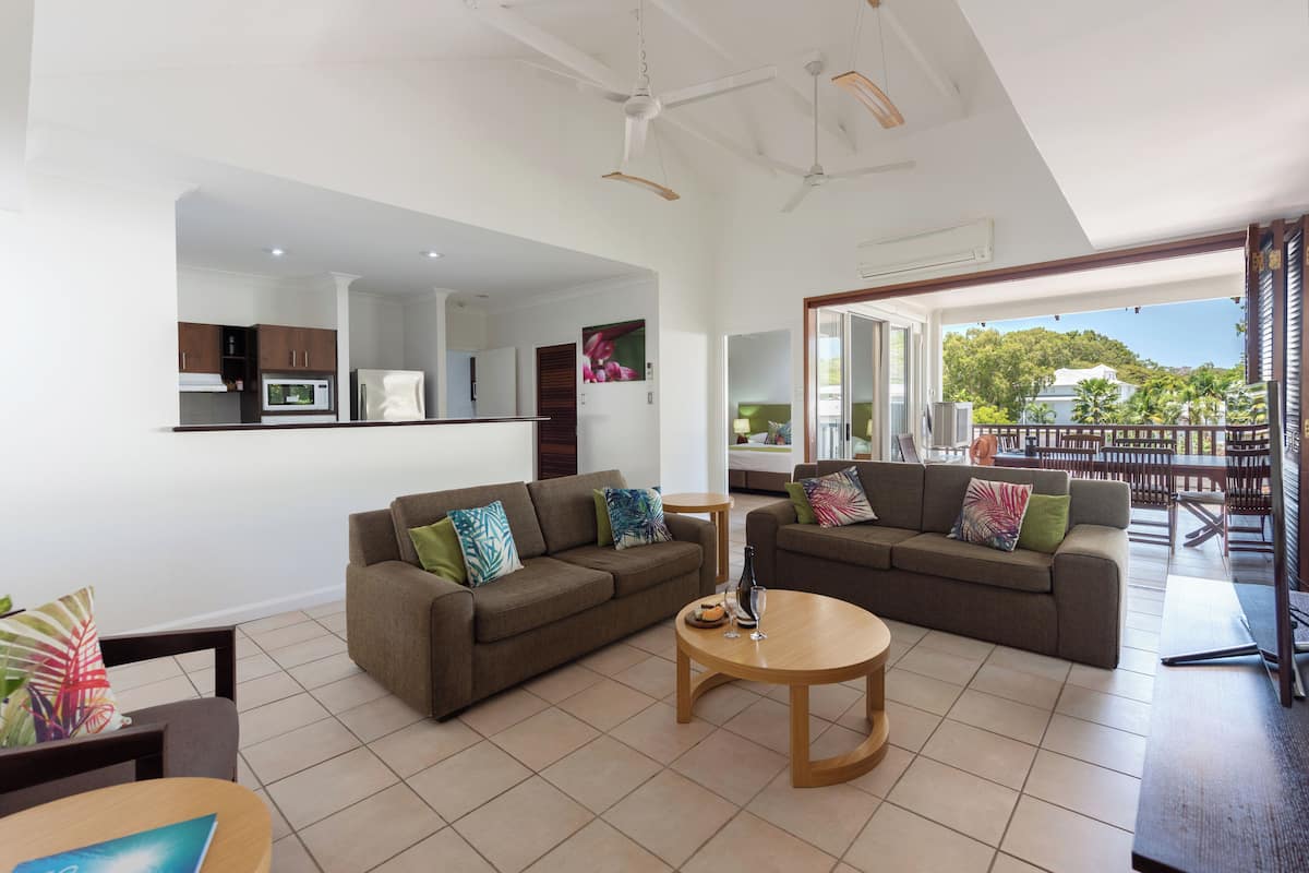A spacious living area with two sofas, a coffee table, and a kitchen in the background.