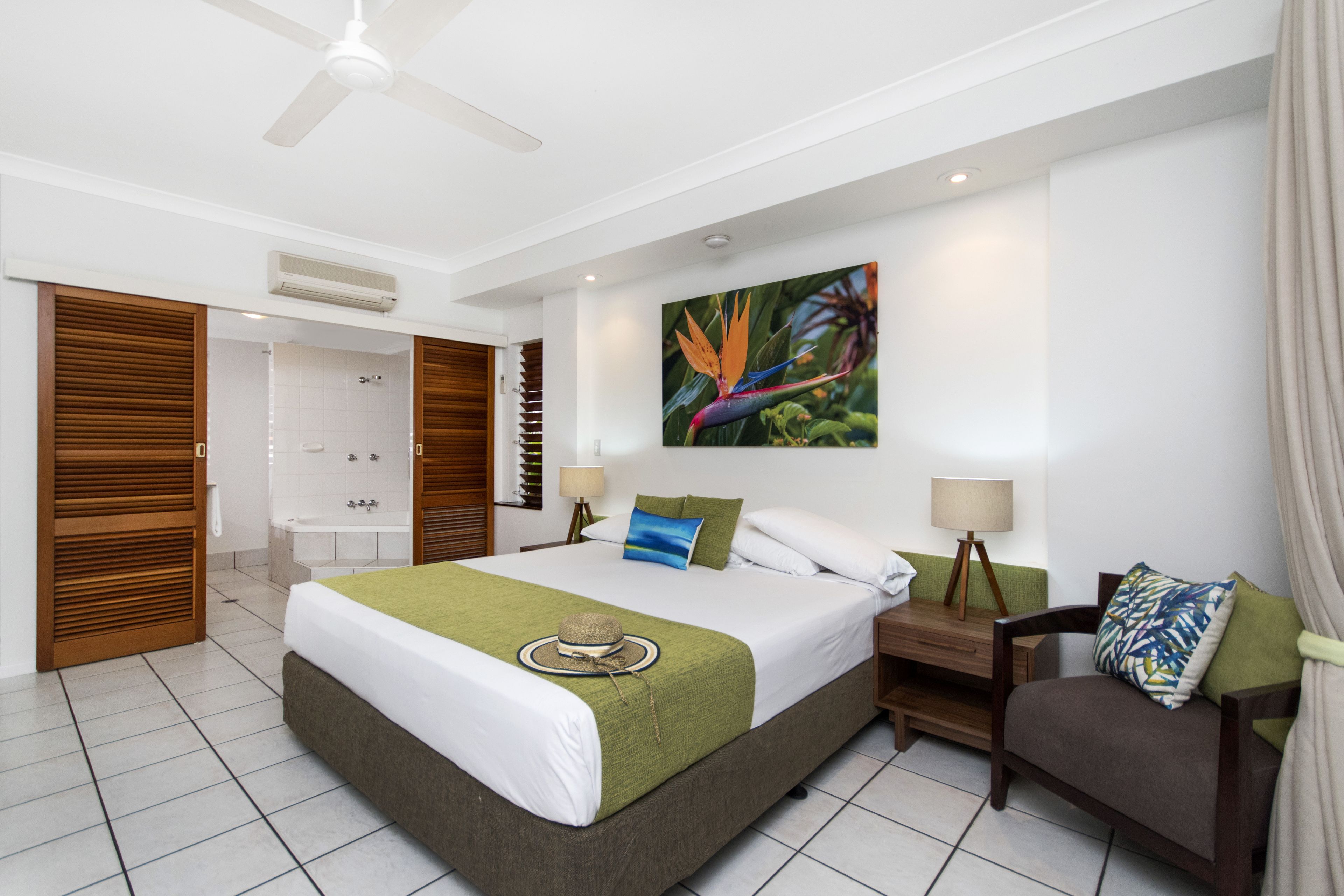 A modern hotel room with a large bed, a shower area, and a view of the outdoors.