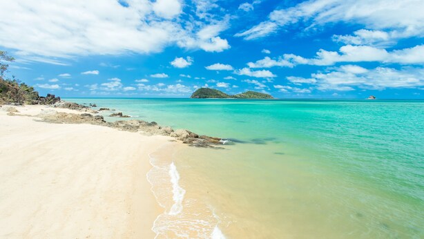 A beach with clear turquoise water, a sandy shore, and a small island in the distance. - The Reef Retreat (Palm Cove)
