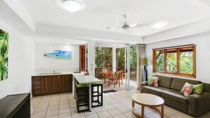 A spacious living area with a sofa, a dining table, and a kitchen area with a sink and cabinets. - The Reef Retreat (Palm Cove)