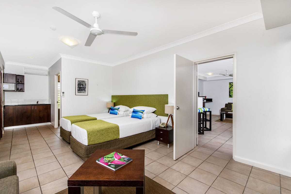 A hotel room with a bed, bedside table, and a view of the adjacent room.