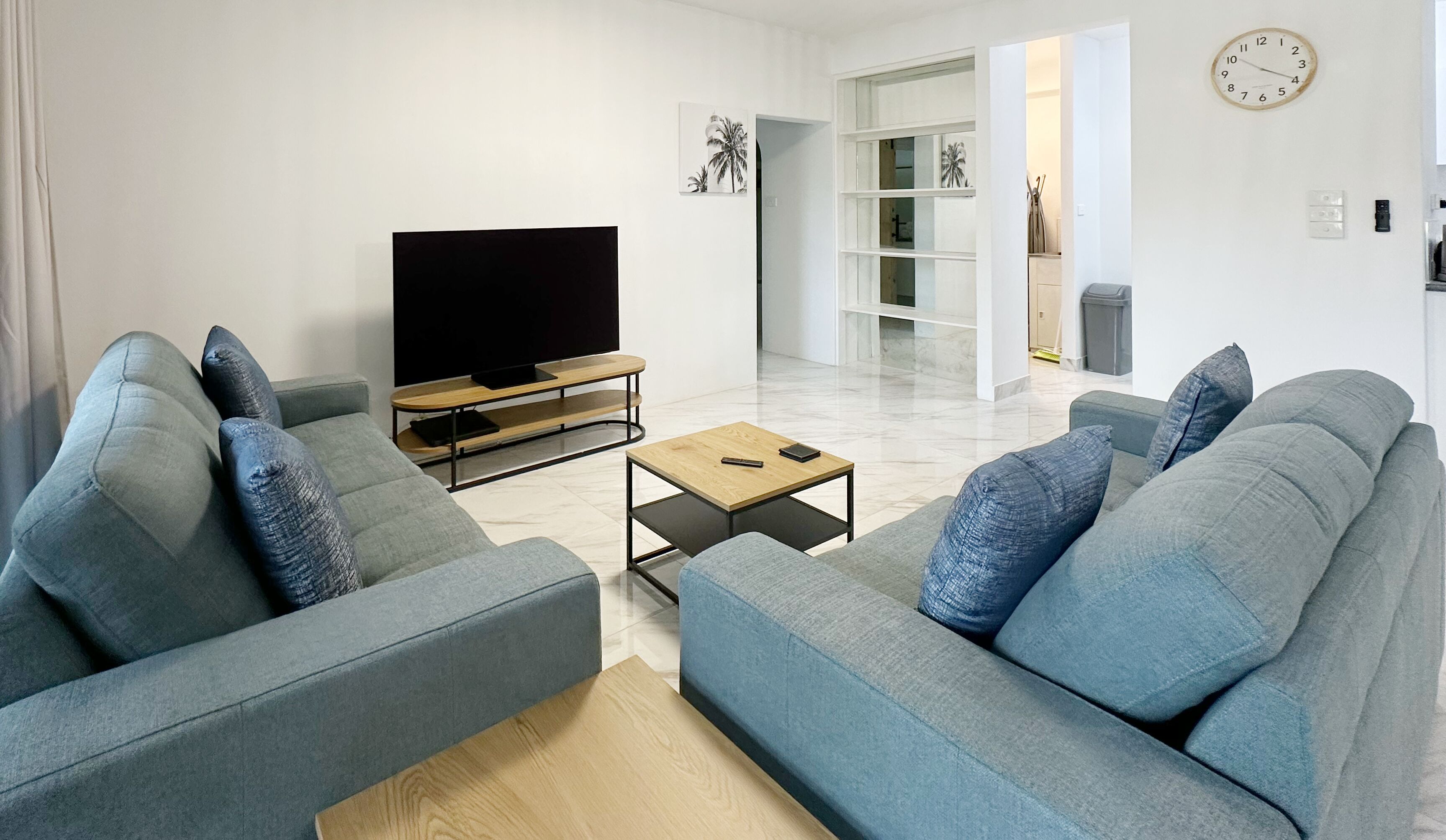 A modern living room with two grey sofas, a wooden coffee table, and a flat-screen TV.