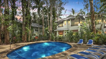 Relax by the serene pool surrounded by lush tropical vegetation and lounge chairs.