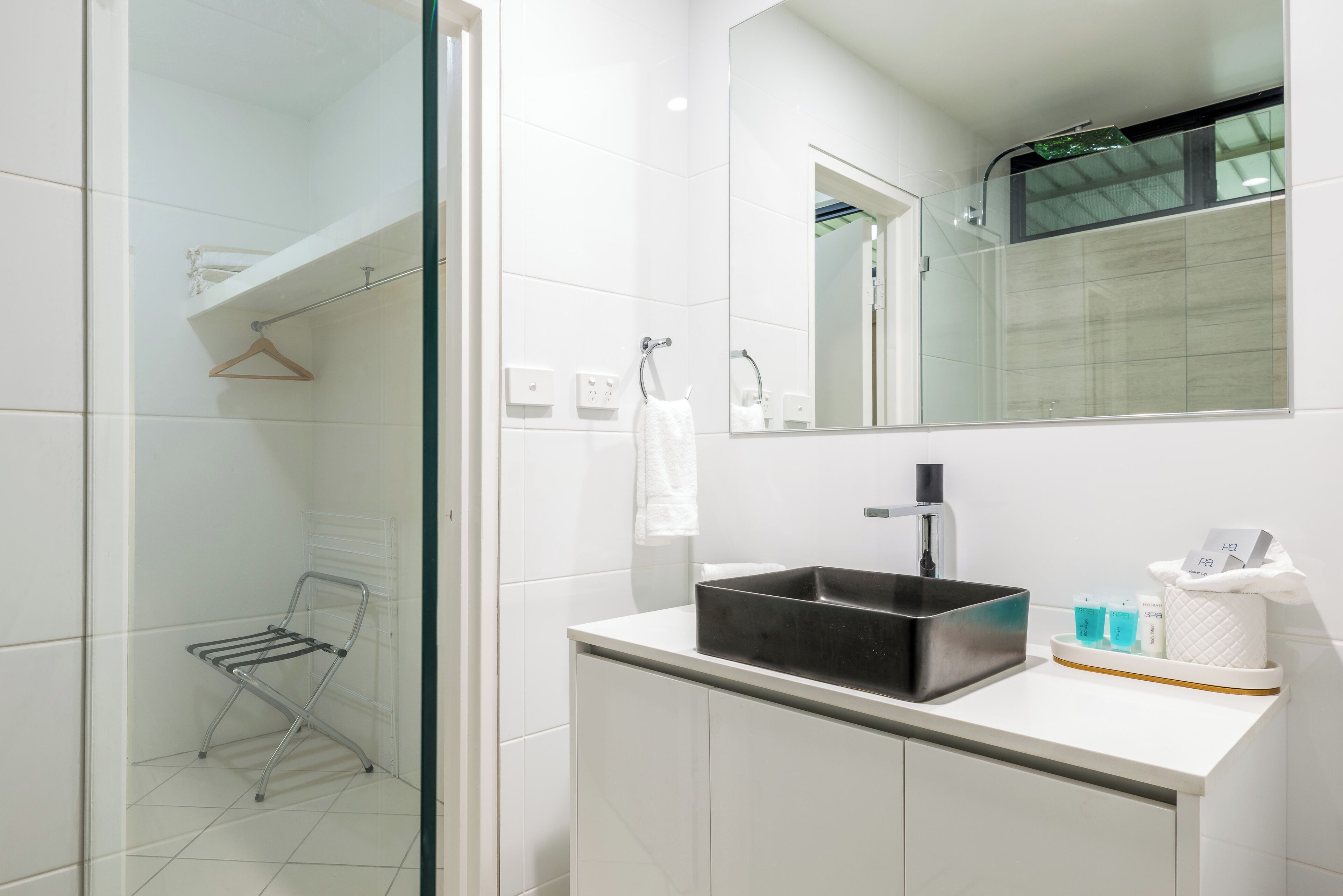 A modern bathroom with a glass shower enclosure, a black sink, and a mirror above the vanity.