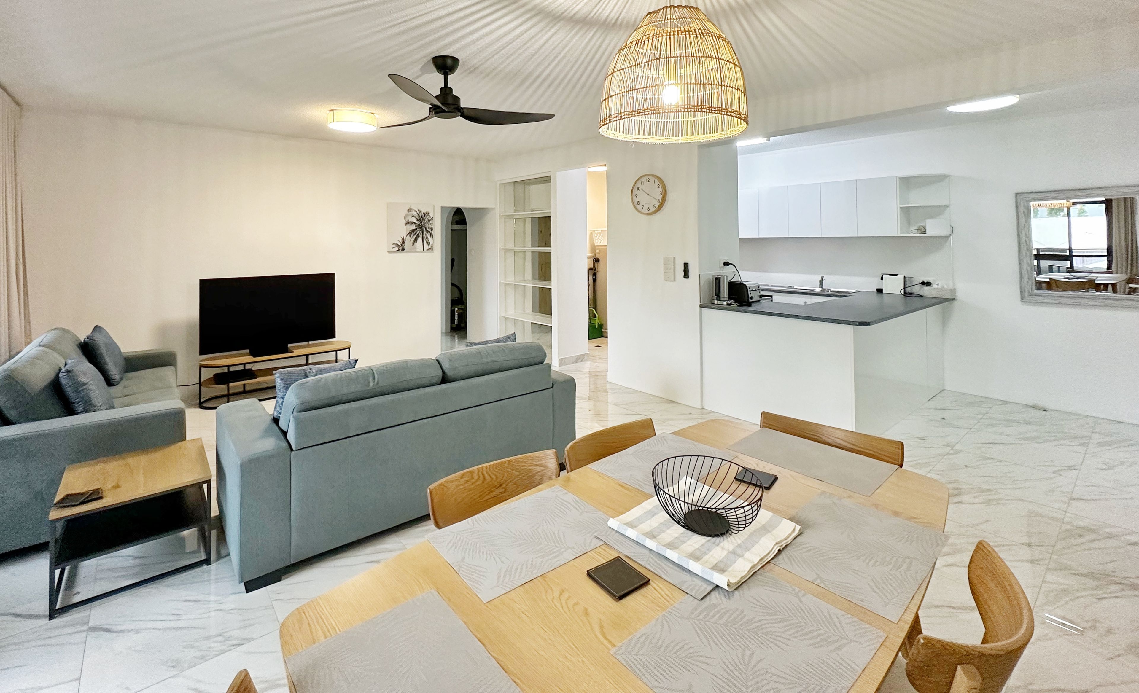 A modern living room with a sofa, TV, and dining area with a table and chairs.
