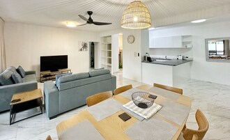A modern living room with a sofa, TV, and dining area with a table and chairs.