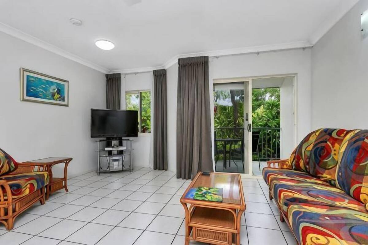 A living room with a television, a sofa, a coffee table, and a balcony door.
