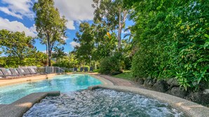 A swimming pool with a hot tub, surrounded by lush greenery and a white fence. - Beachfront Apartments on Trinity Beach (Trinity Beach)