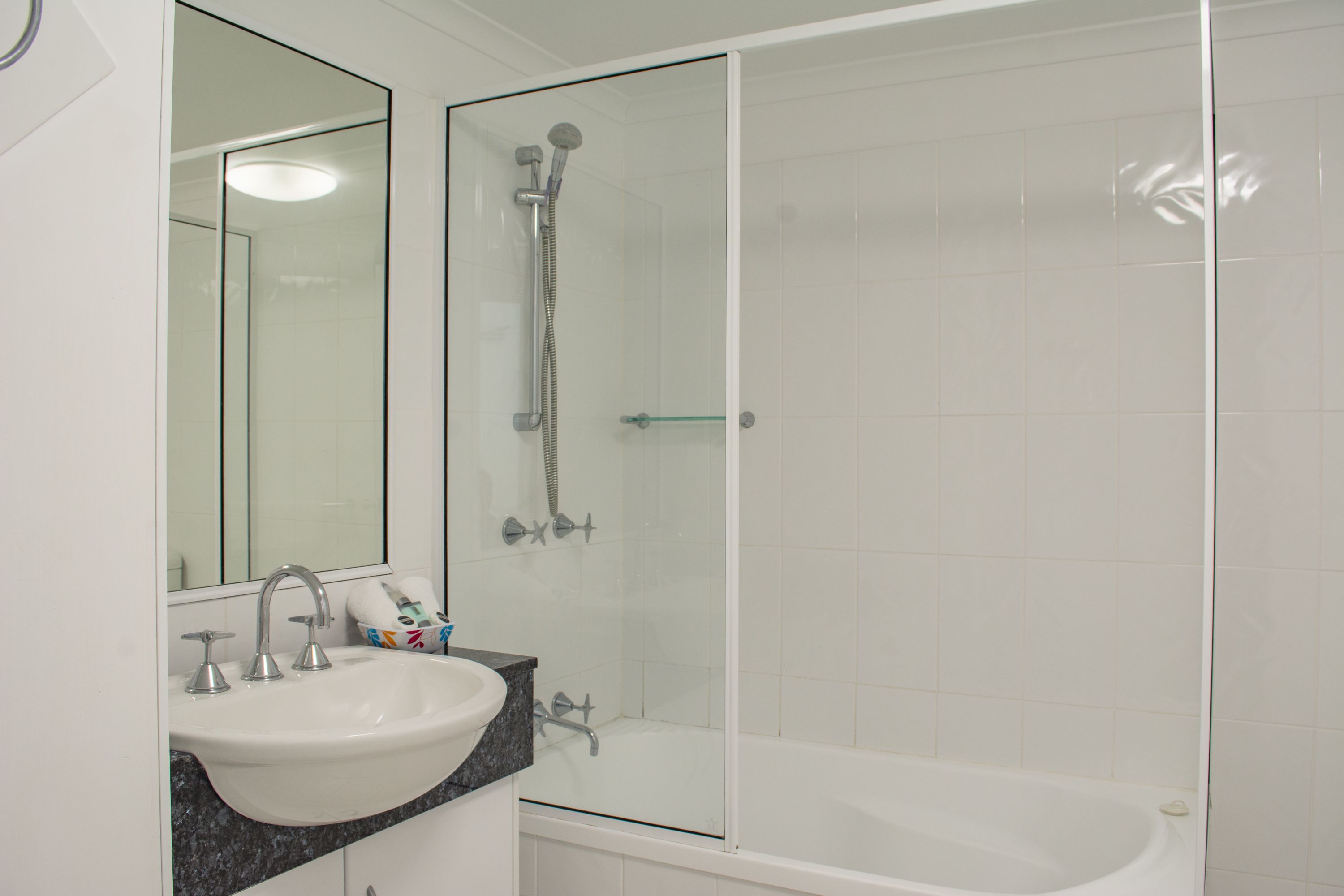 A modern bathroom with a glass-enclosed shower, a white sink, and a bathtub.