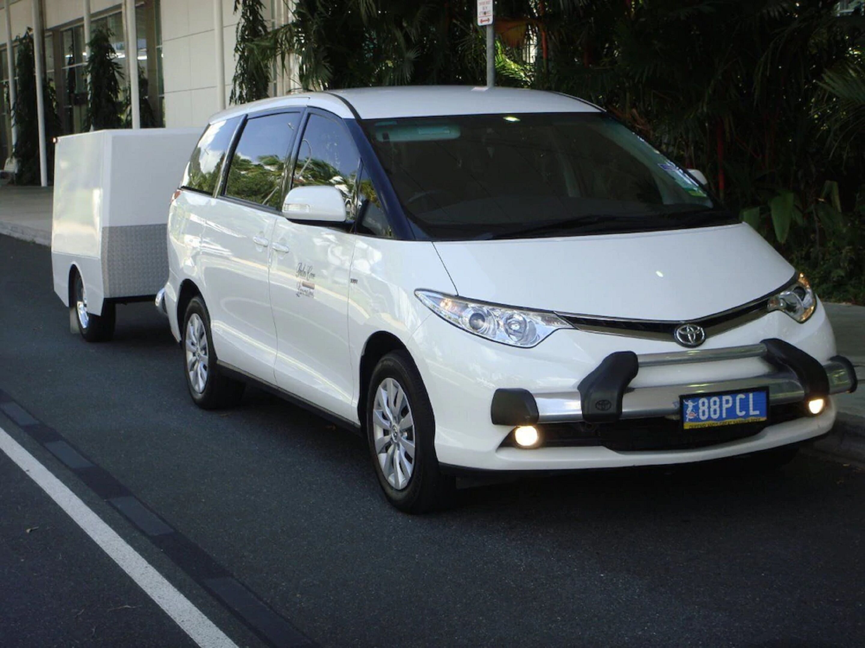 Une Toyota blanche tirant une remorque sur une route.