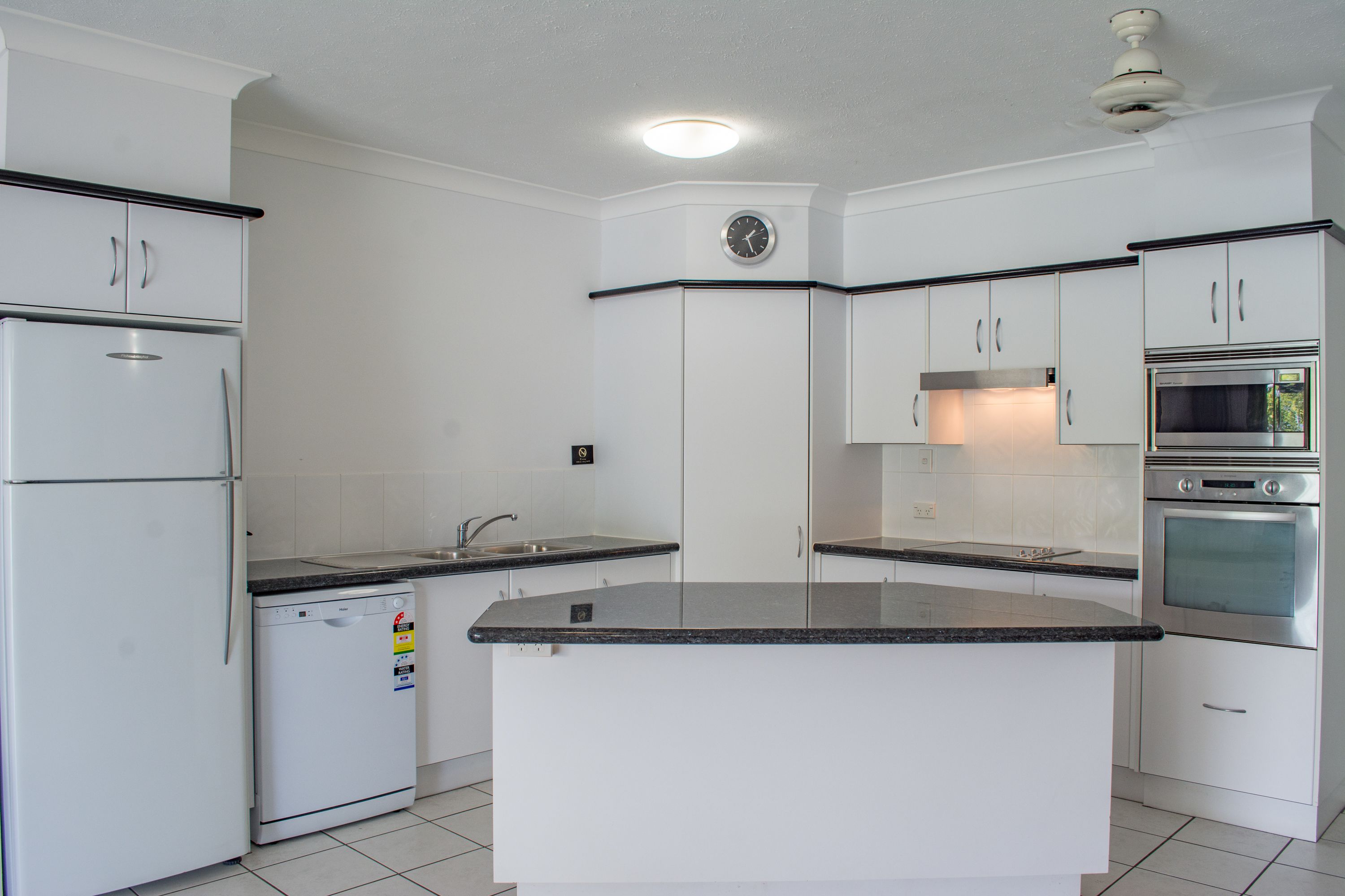 A kitchen with white cabinets, a built-in oven, a microwave, and a dishwasher.