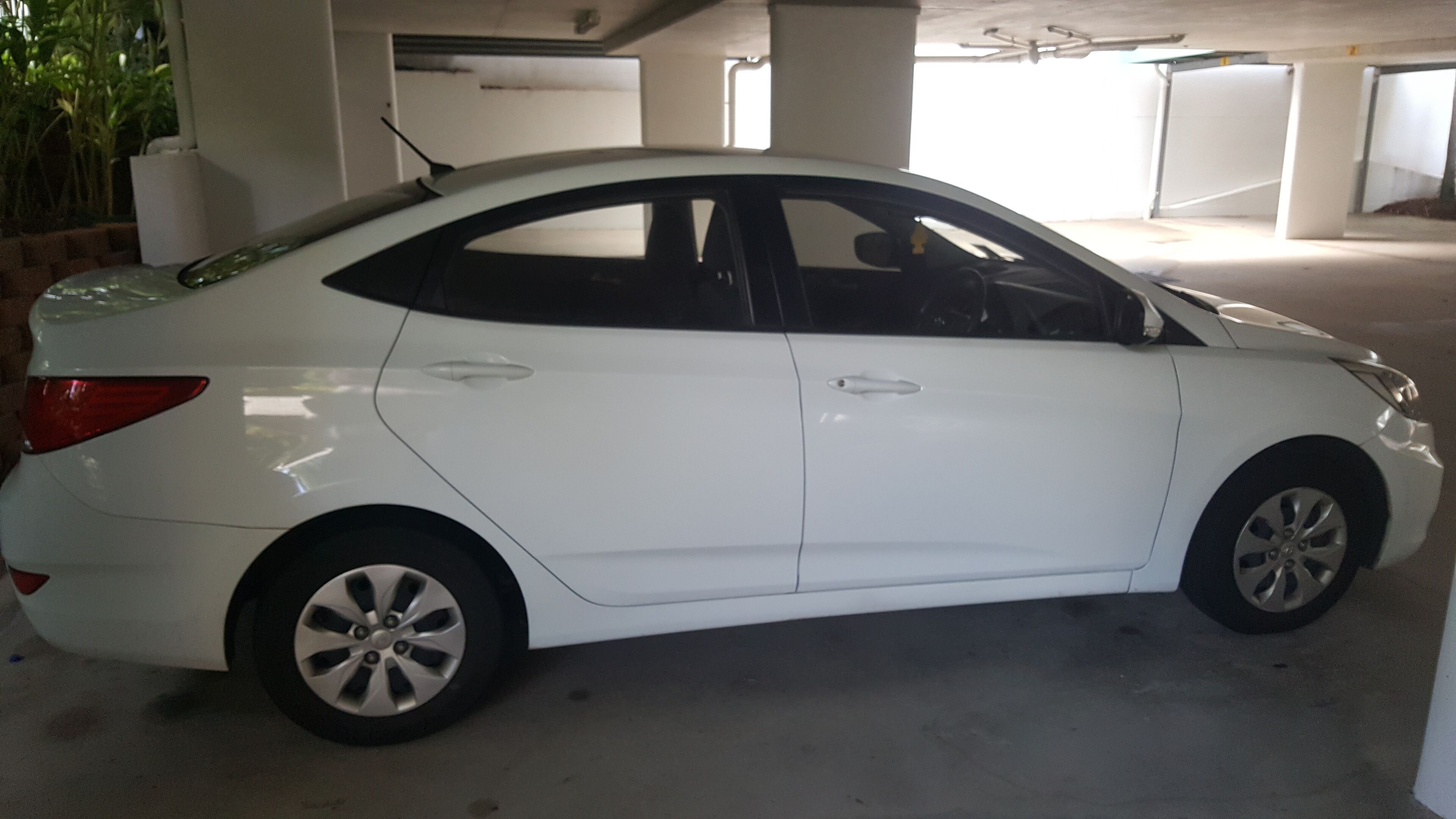 A white car parked in a multi-level parking garage.