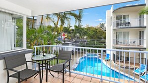 A balcony with a pool, chairs, and a table. - Beachside Mooloolaba (Mooloolaba)