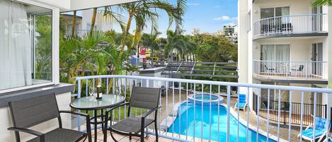 A balcony with a pool, chairs, and a table.
