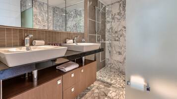 A modern bathroom with two sinks, a large mirror, and a shower area.