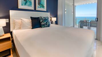 A large bed with white linens, a headboard, and two wall-mounted paintings.