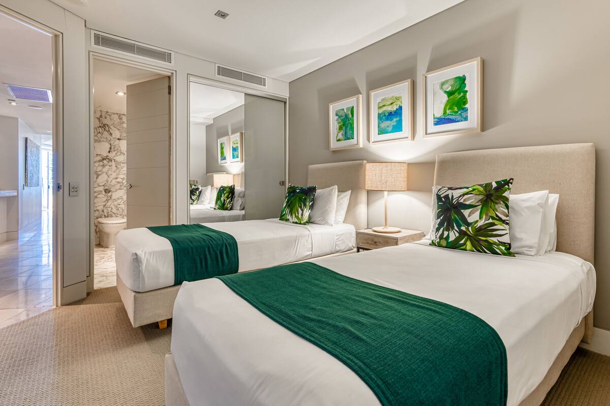 Habitación de hotel con dos camas, un espejo grande y obras de arte en la pared.