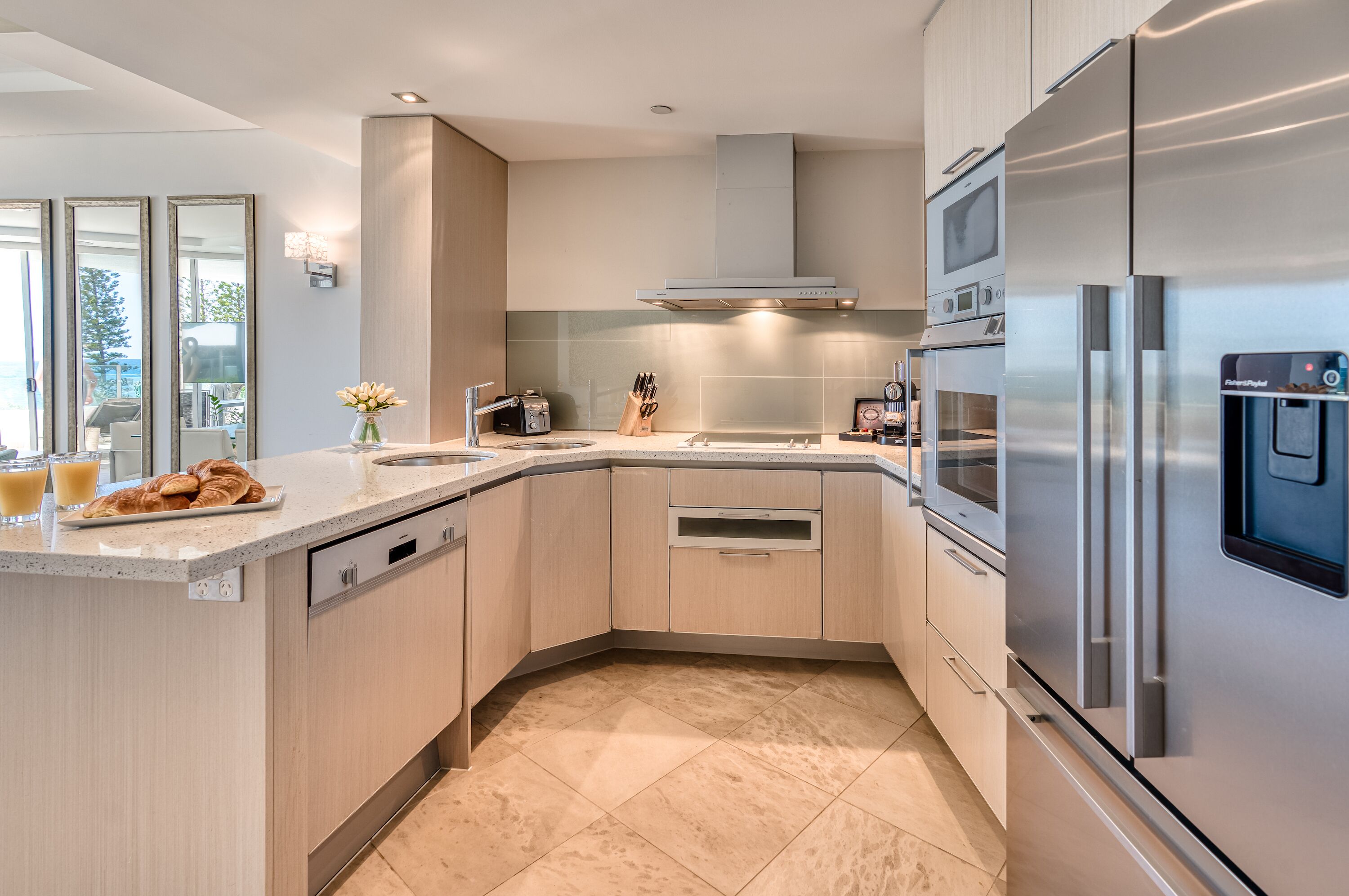 Una cocina moderna con refrigerador de acero inoxidable, horno empotrado y una isla grande con pileta.