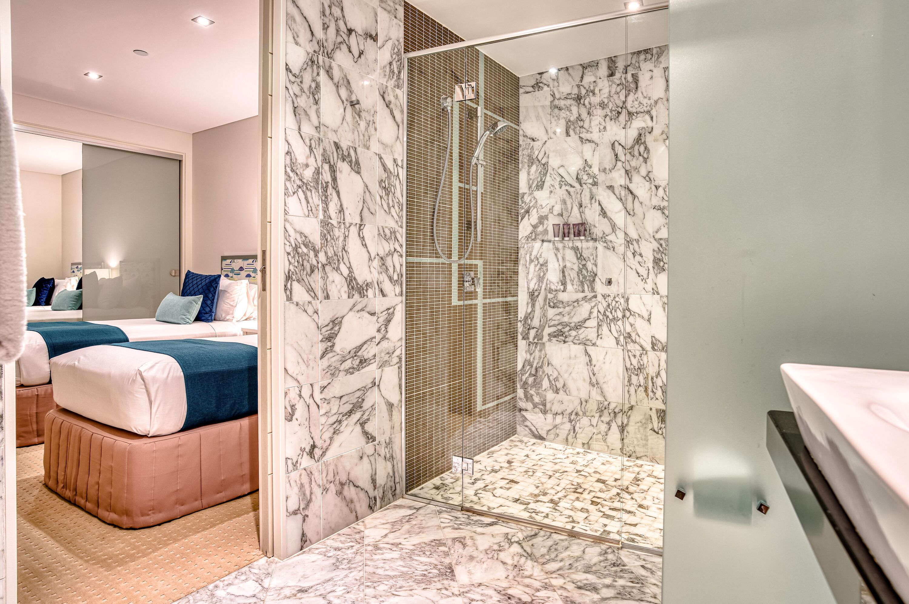 Une salle de bain moderne avec une douche à parois de verre, des murs en marbre et un grand miroir.