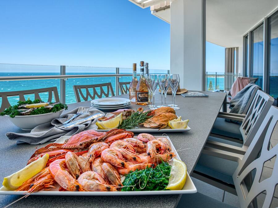Una mesa de comedor con mariscos, vino y copas, con vista al mar.