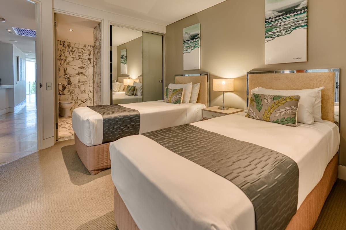 Habitación de hotel con dos camas, pared de mármol y obras de arte en las paredes.