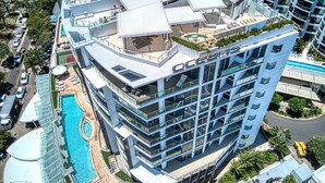 A modern hotel with multiple floors, rooftop amenities, and a swimming pool.