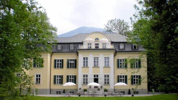 A large, yellow building with a symmetrical facade, multiple windows, and a central entrance.
