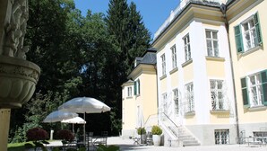 A courtyard with outdoor seating, a staircase, and a building with ornate railings.