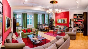 A spacious living room with a red accent wall, a dining area, and a bookshelf filled with books.