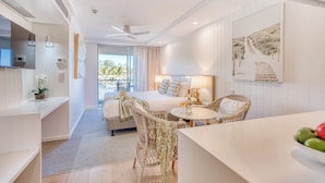Une chambre d’hôtel moderne équipée d’un lit, d’un coin repas, d’une télévision et d’un balcon avec vue.