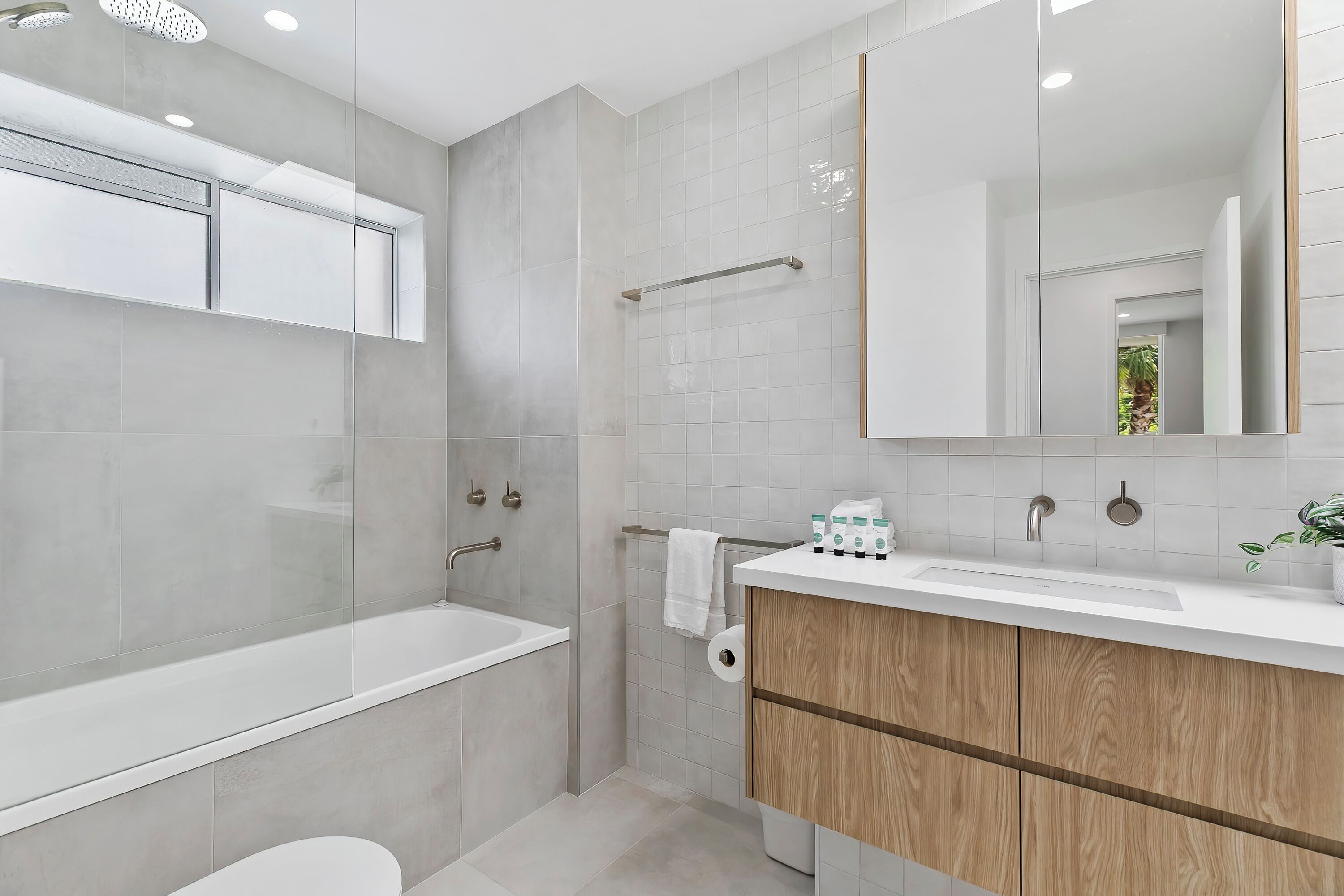 Un baño moderno con bañera, lavamanos con espejo e inodoro.