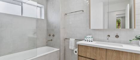 Un baño moderno con bañera, lavamanos con espejo e inodoro.
