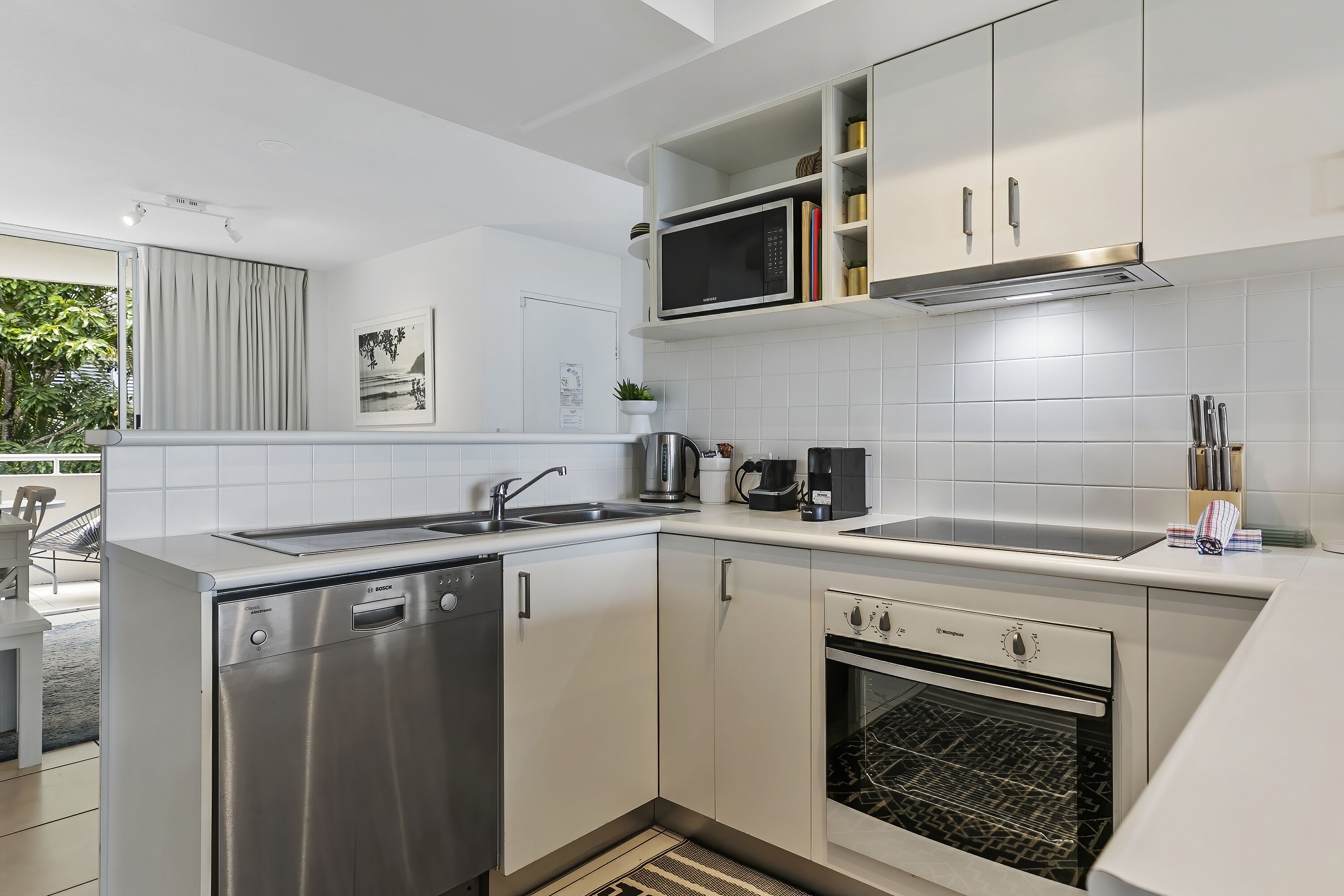 Una cucina compatta con lavastoviglie, forno, microonde e un piccolo lavello.